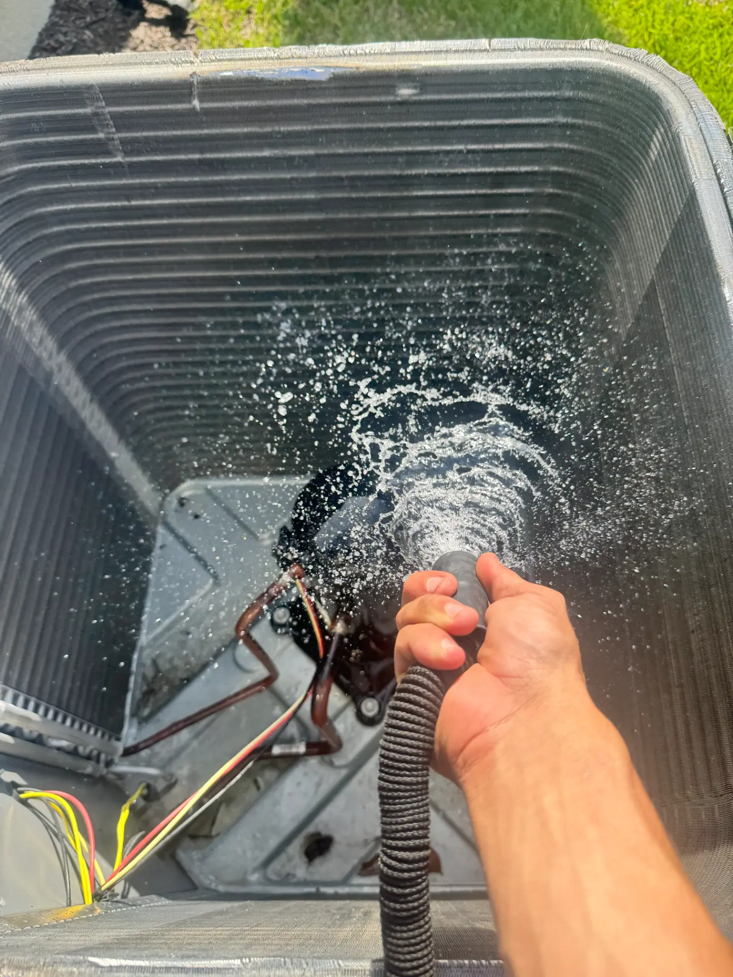 Deep cleaning of an outdoor AC condenser coil, sprayed by hand with a hose